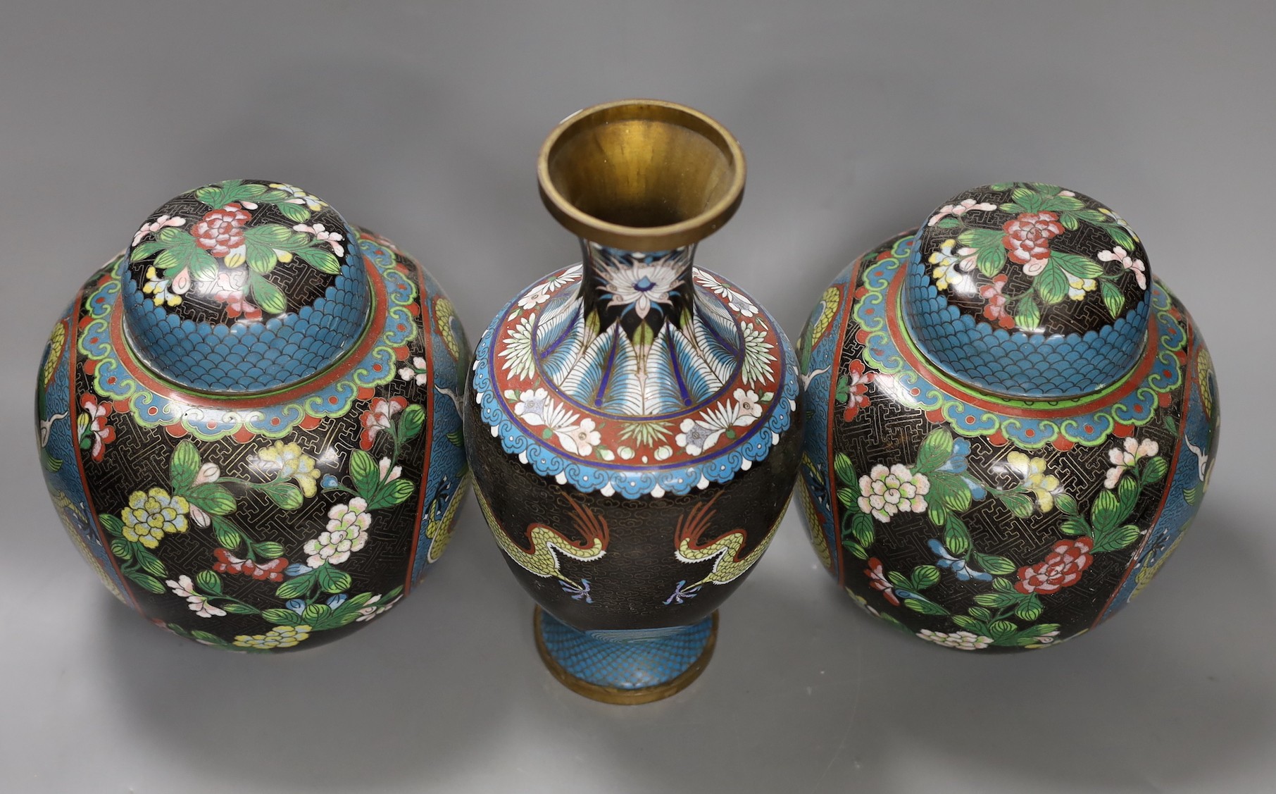 A pair of early 20th century Chinese cloisonné enamel ‘dragon’ jars and covers and a similar vase. Tallest 25.5cm